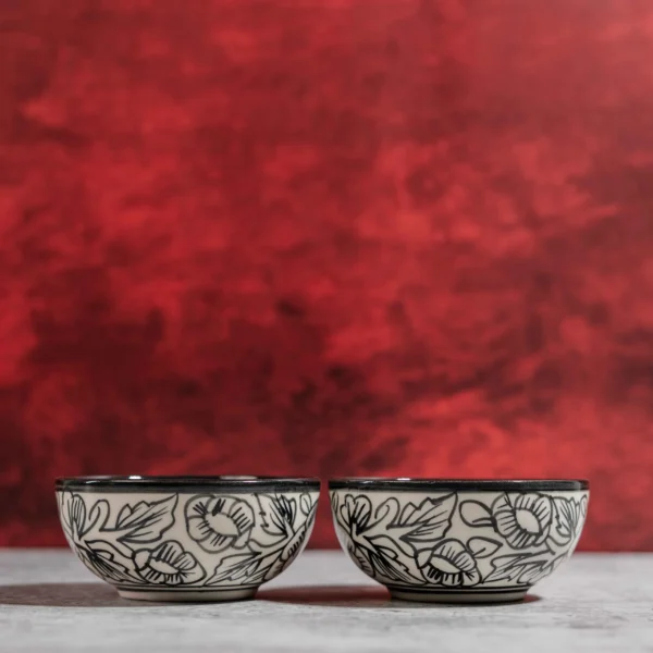 Monarca Ceramic Katori Bowls – Set of 2 by Harmiche. Hand-painted black floral design, microwave & dishwasher safe. Perfect for curries, dal & desserts.